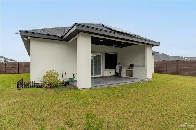 back of house featuring ceiling fan, a patio area, and a lawn