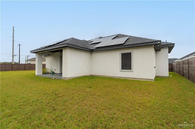 back of property featuring a lawn and solar panels