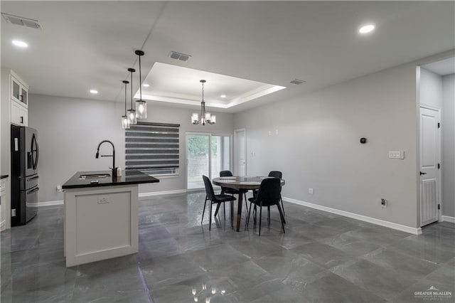 dining area with sink, a notable chandelier, and a tray ceiling