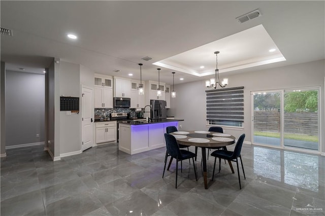 dining area with an inviting chandelier and a tray ceiling