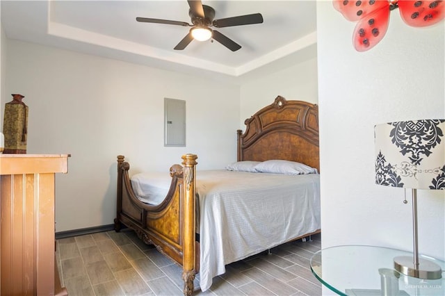 bedroom featuring a tray ceiling, electric panel, and ceiling fan