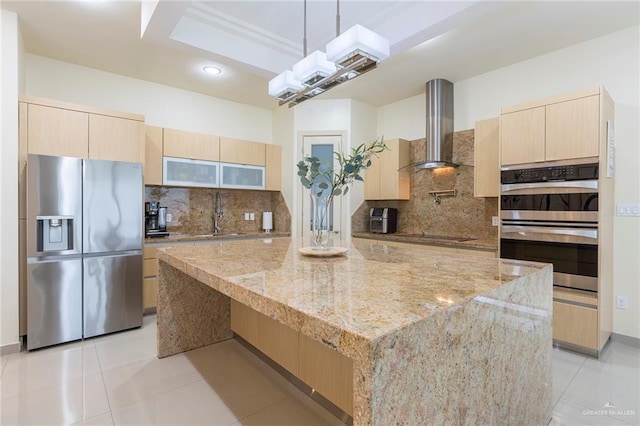 kitchen featuring light stone countertops, backsplash, wall chimney exhaust hood, stainless steel appliances, and sink