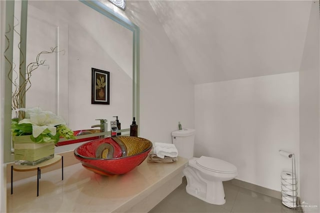 bathroom with tile patterned flooring, toilet, sink, and vaulted ceiling