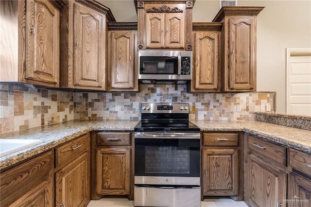 kitchen featuring stainless steel appliances, tasteful backsplash, and light stone counters