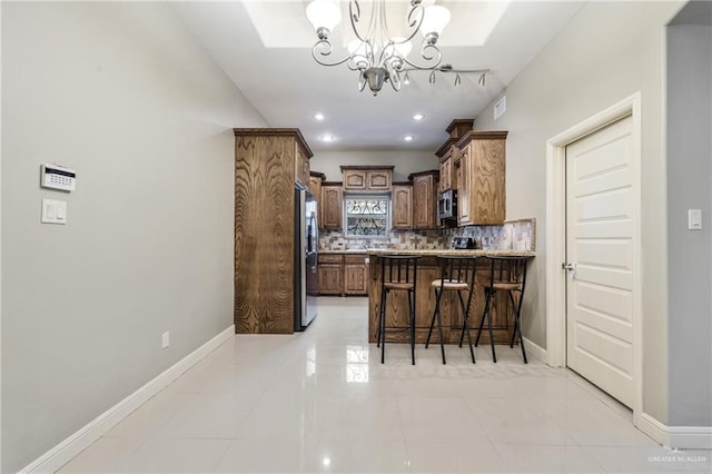 kitchen with appliances with stainless steel finishes, a breakfast bar, backsplash, light tile patterned floors, and kitchen peninsula