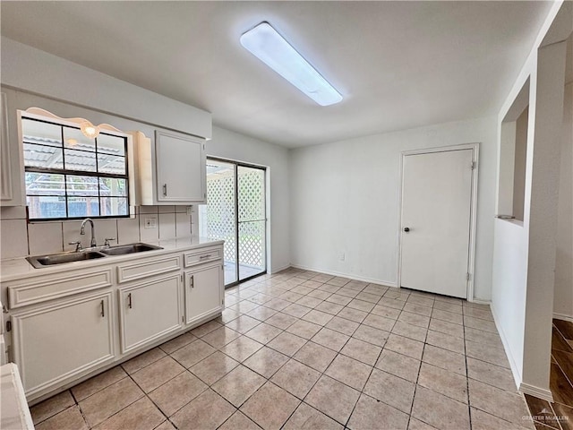 1313 Royal Palm St, Alamo, TX 78516 - kitchen featuring a sink, light countertops, white cabinets, light tile patterned flooring, and decorative backsplash