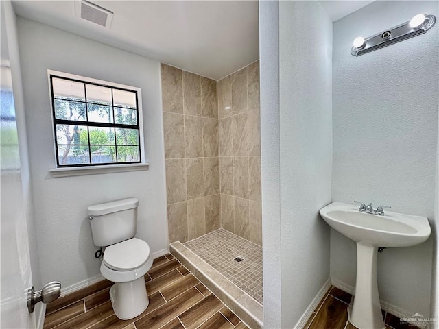 1313 Royal Palm St, Alamo, TX 78516 - bathroom featuring toilet, tiled shower, wood tiled floors, and baseboards