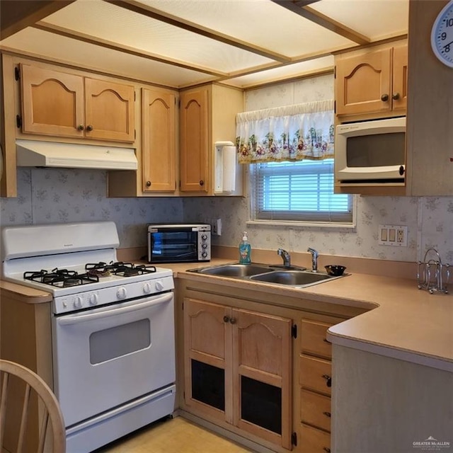 kitchen featuring light brown cabinets, white appliances, and sink