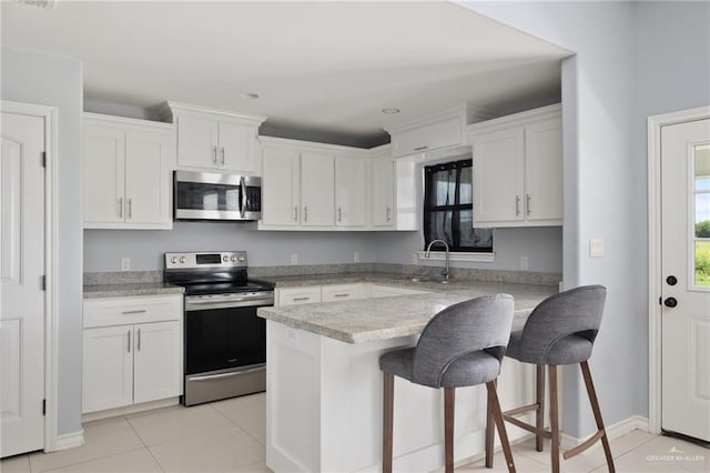 23309 Tangerine Ave, Harlingen, TX 78552 - kitchen featuring appliances with stainless steel finishes, white cabinets, light tile patterned floors, a kitchen bar, and light stone counters
