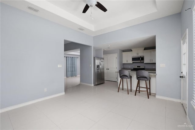 23309 Tangerine Ave, Harlingen, TX 78552 - kitchen with stainless steel appliances, a kitchen bar, ceiling fan, a raised ceiling, and dark countertops