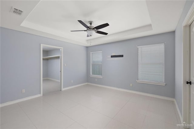 23309 Tangerine Ave, Harlingen, TX 78552 - unfurnished bedroom featuring a raised ceiling, ceiling fan, tile patterned floors, a closet, and a walk in closet