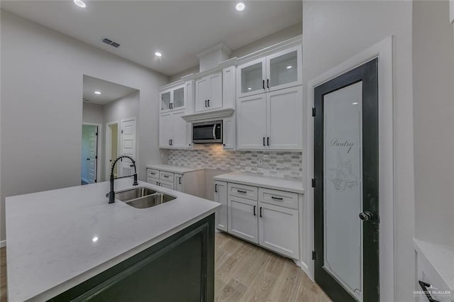 kitchen featuring backsplash, light wood-type flooring, sink, and white cabinets