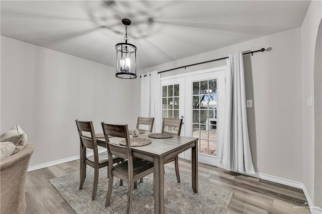 dining space with french doors, light wood-style flooring, and baseboards