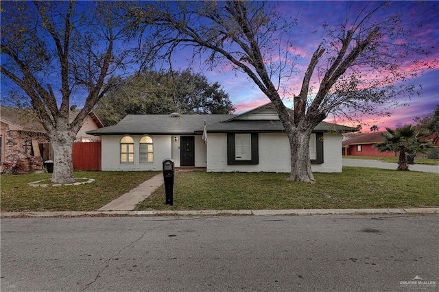 single story home with brick siding, a lawn, and fence