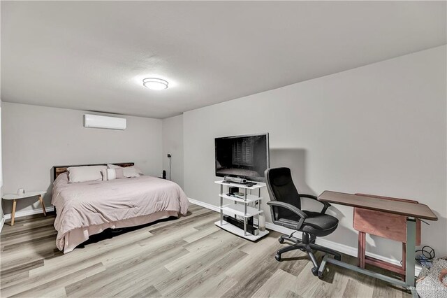 bedroom with baseboards, wood finished floors, and a wall mounted AC