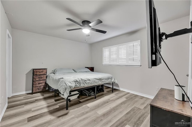 bedroom with light wood finished floors, a ceiling fan, and baseboards