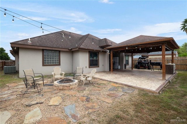 rear view of property featuring a gazebo, central AC, a fire pit, and a patio area