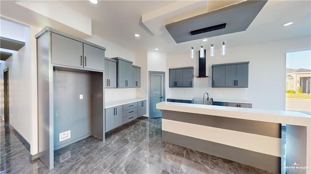 kitchen with gray cabinets, decorative light fixtures, sink, and wall chimney exhaust hood