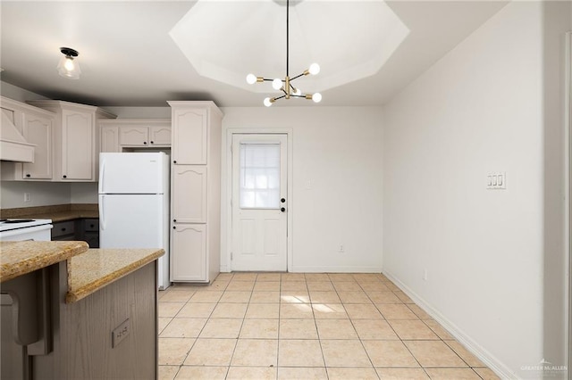 kitchen with white refrigerator, light tile patterned flooring, light stone countertops, and white cabinets