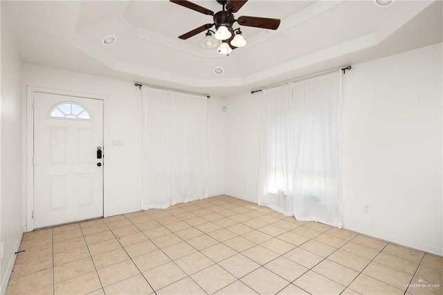 unfurnished room with a raised ceiling, plenty of natural light, and ceiling fan