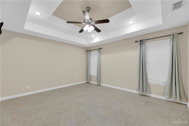 spare room with ceiling fan and a raised ceiling