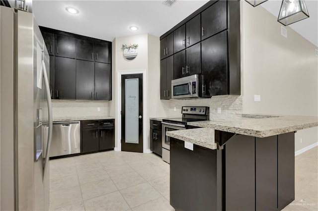 kitchen with appliances with stainless steel finishes, kitchen peninsula, a breakfast bar area, and backsplash