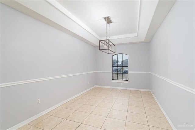 unfurnished dining area featuring a chandelier, light tile patterned floors, and a tray ceiling