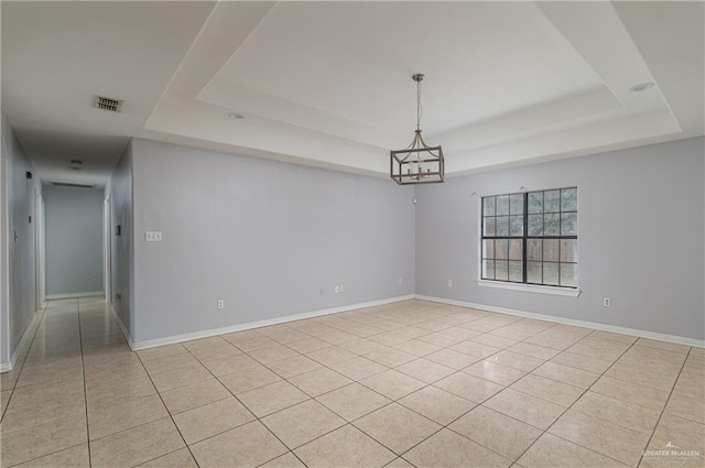 tiled spare room with an inviting chandelier and a raised ceiling