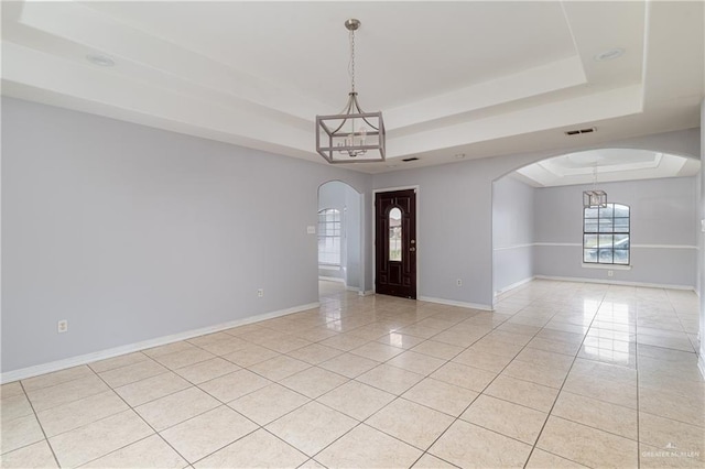 entryway with light tile patterned floors, an inviting chandelier, and a raised ceiling