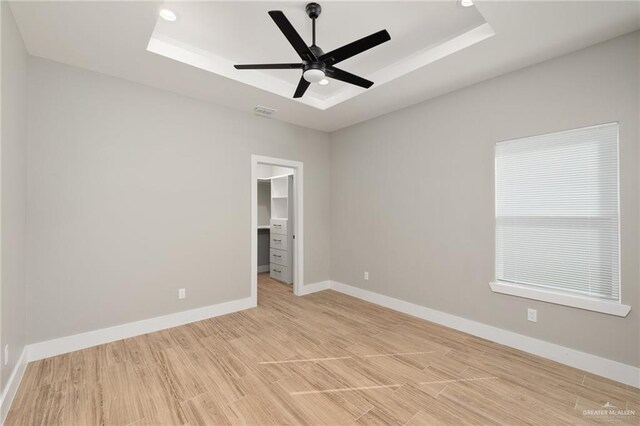 unfurnished room featuring light wood-type flooring, a raised ceiling, visible vents, and baseboards