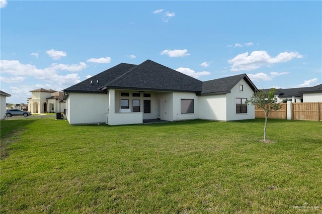 back of house with a yard, fence, and stucco siding