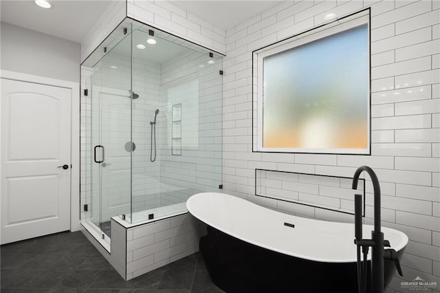 full bath featuring a stall shower, a freestanding tub, tile walls, and recessed lighting