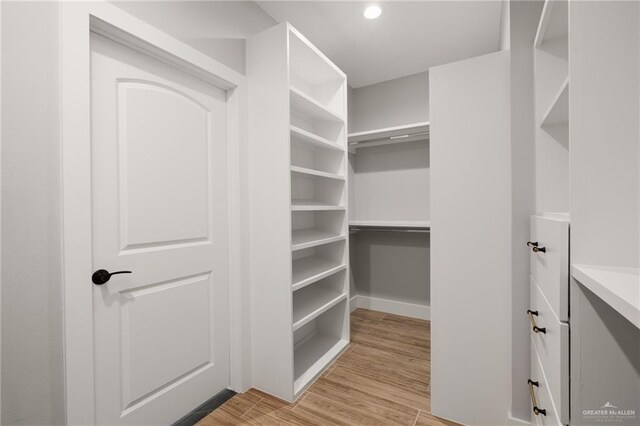 walk in closet with light wood finished floors