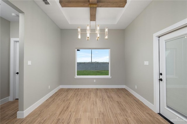 unfurnished dining area featuring a tray ceiling, visible vents, light wood finished floors, and baseboards