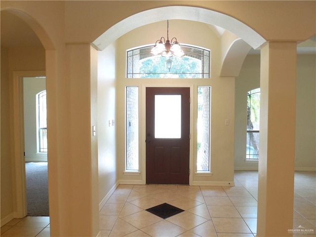 tiled foyer featuring a healthy amount of sunlight and an inviting chandelier