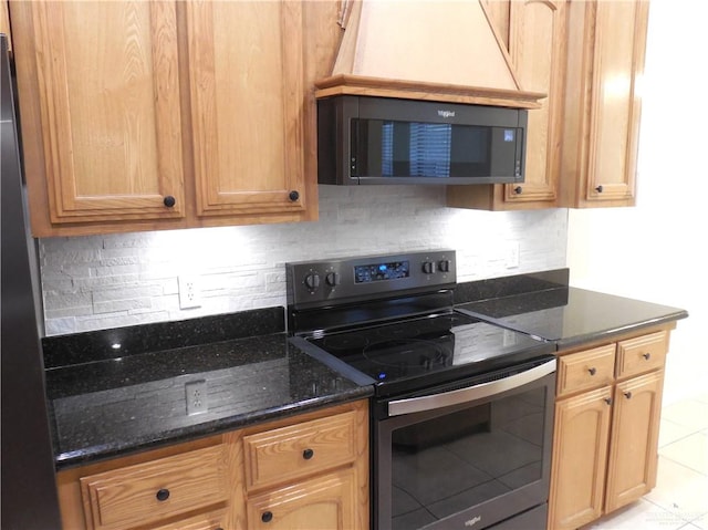 kitchen featuring tasteful backsplash, dark stone countertops, light tile patterned flooring, and stainless steel appliances