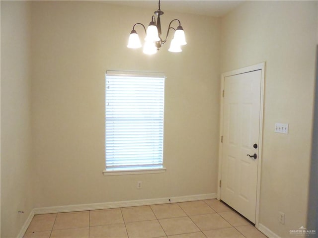 tiled spare room with a wealth of natural light and a chandelier