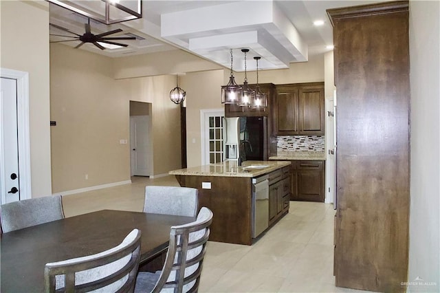 kitchen featuring light stone countertops, stainless steel appliances, tasteful backsplash, an island with sink, and decorative light fixtures