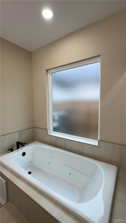 bathroom featuring tile patterned flooring and a relaxing tiled tub