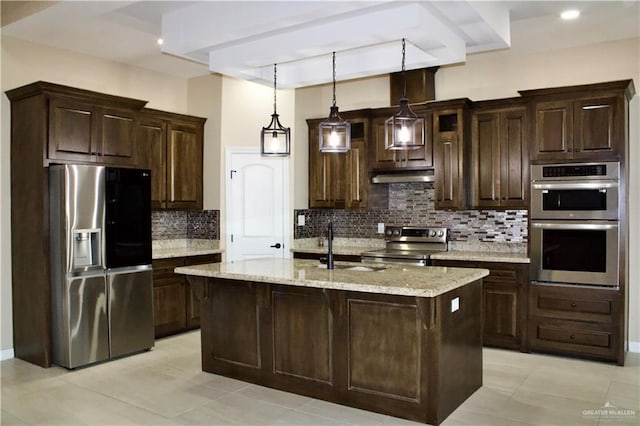 kitchen featuring a center island with sink, light stone counters, dark brown cabinetry, and stainless steel appliances