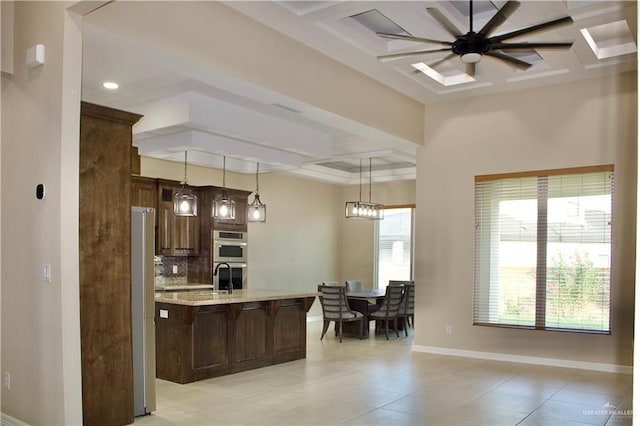 kitchen with tasteful backsplash, light stone counters, plenty of natural light, and coffered ceiling