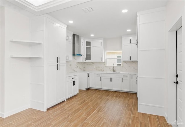 kitchen featuring white cabinetry, sink, decorative backsplash, and wall chimney exhaust hood