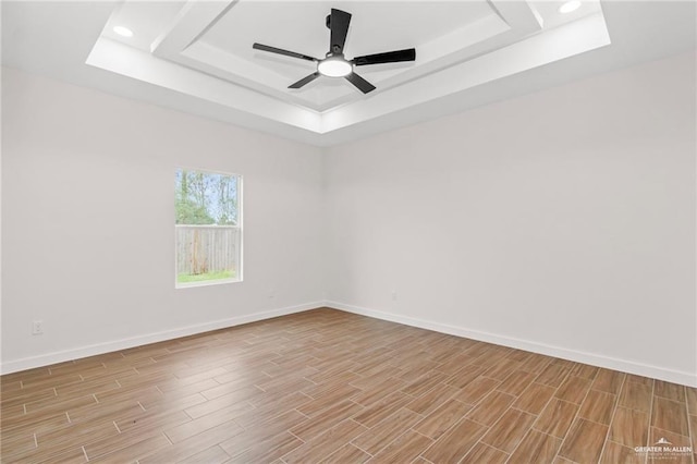 empty room featuring ceiling fan and a tray ceiling