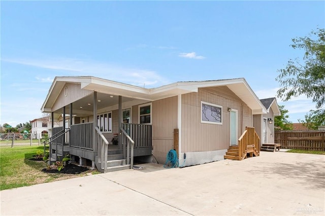 view of front facade with covered porch, driveway, and fence