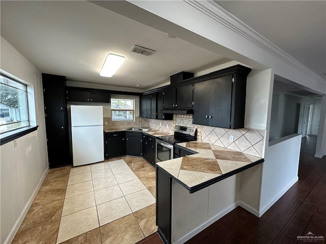 kitchen featuring visible vents, tasteful backsplash, stainless steel range with electric cooktop, freestanding refrigerator, and dark cabinets