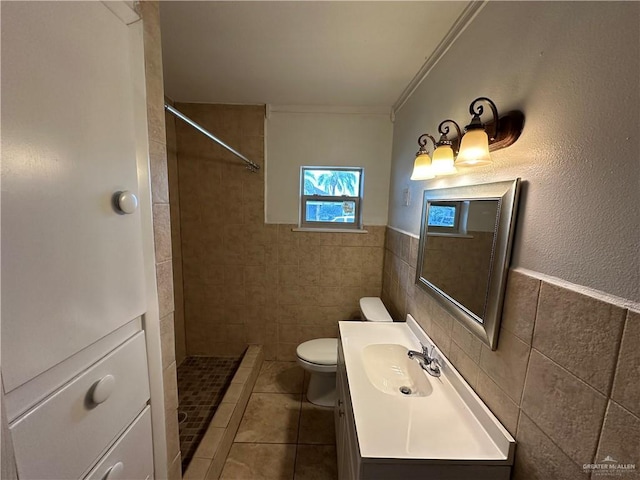 bathroom featuring vanity, tiled shower, tile walls, toilet, and tile patterned floors