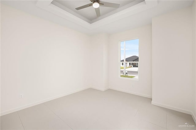 unfurnished room with tile patterned flooring, a raised ceiling, and ceiling fan