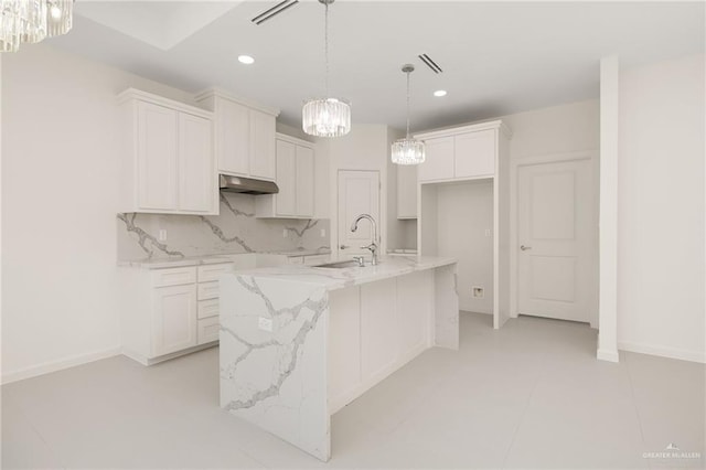 kitchen featuring a center island with sink, backsplash, white cabinetry, and sink