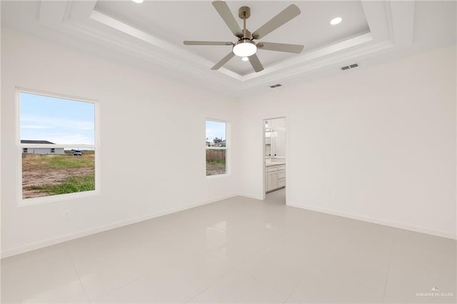 unfurnished room with a raised ceiling, ceiling fan, and light tile patterned floors