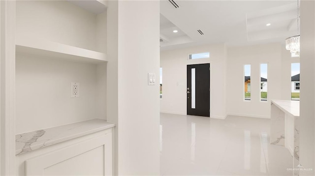 corridor featuring a raised ceiling and an inviting chandelier